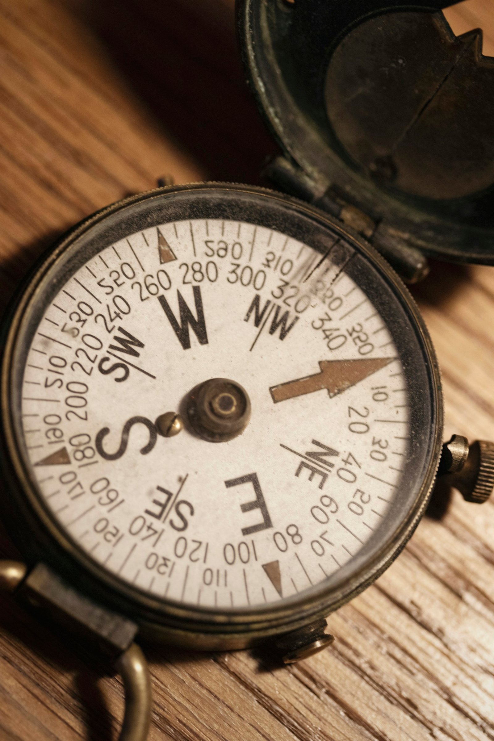 A vintage brass compass resting on a wooden surface