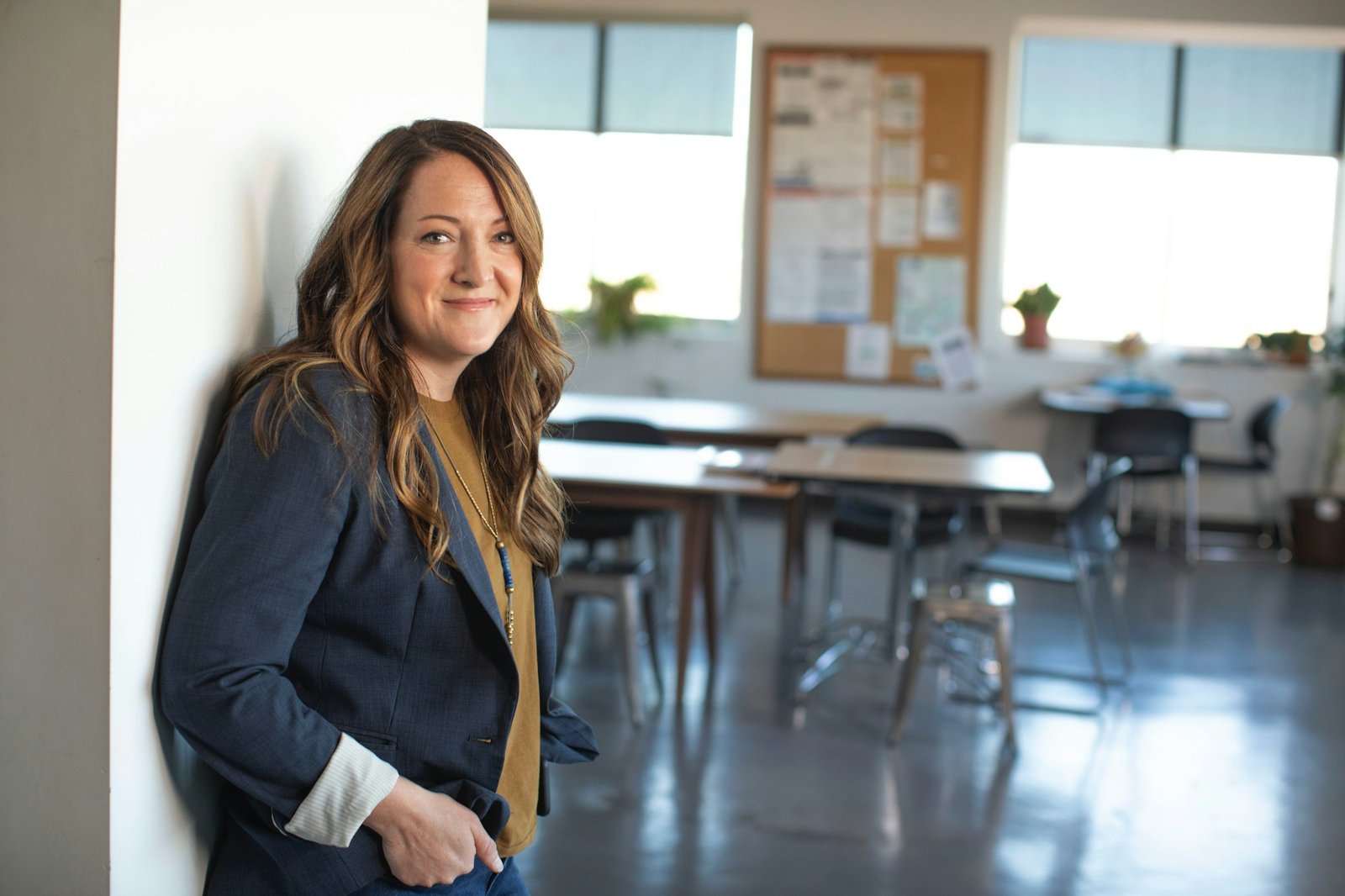 An educator standing thoughtfully in her classroom
