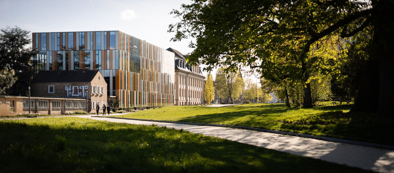A modern university campus building framed by autumn trees